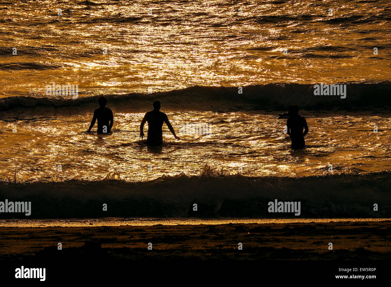 I nuotatori in mare come il sole tramonta in Newquay, Cornwall. Foto Stock