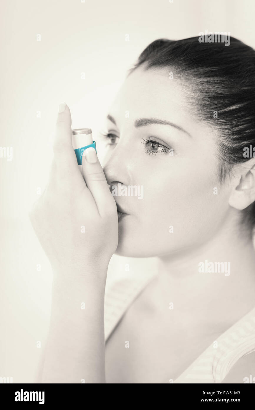 Donna con asma usando un inalatore per asmatici Foto Stock