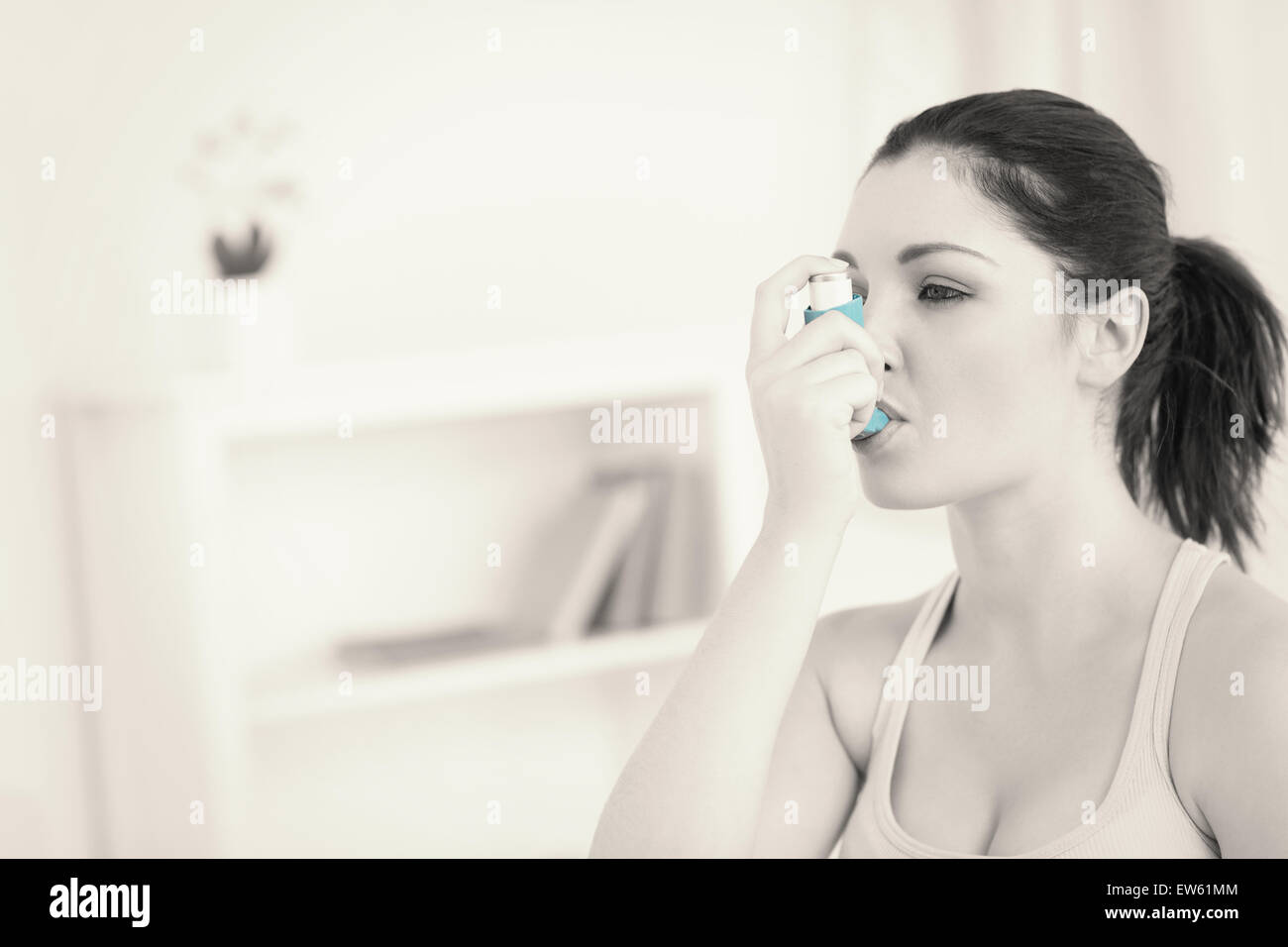 Donna che utilizza l'asma inalatore in salotto Foto Stock
