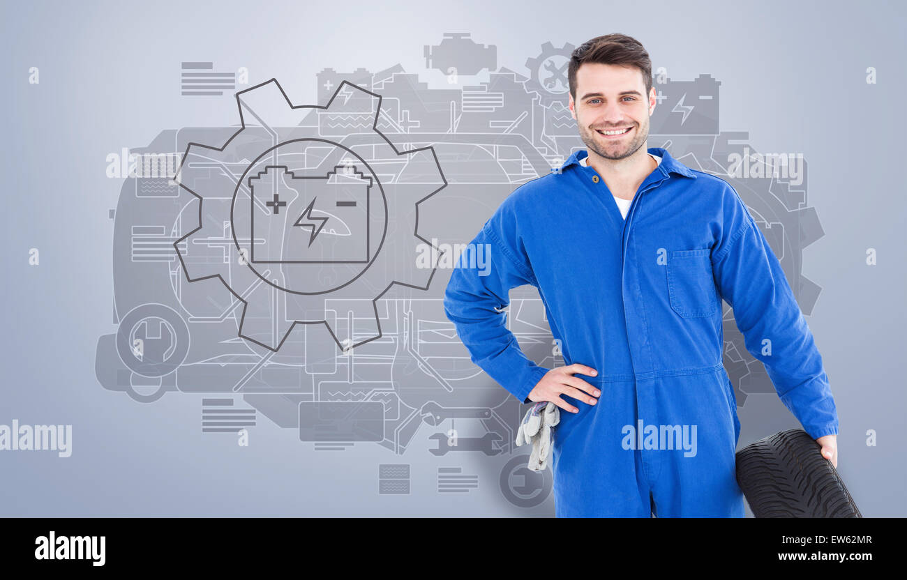 Immagine composita di sorridere meccanico maschio di contenimento del pneumatico Foto Stock