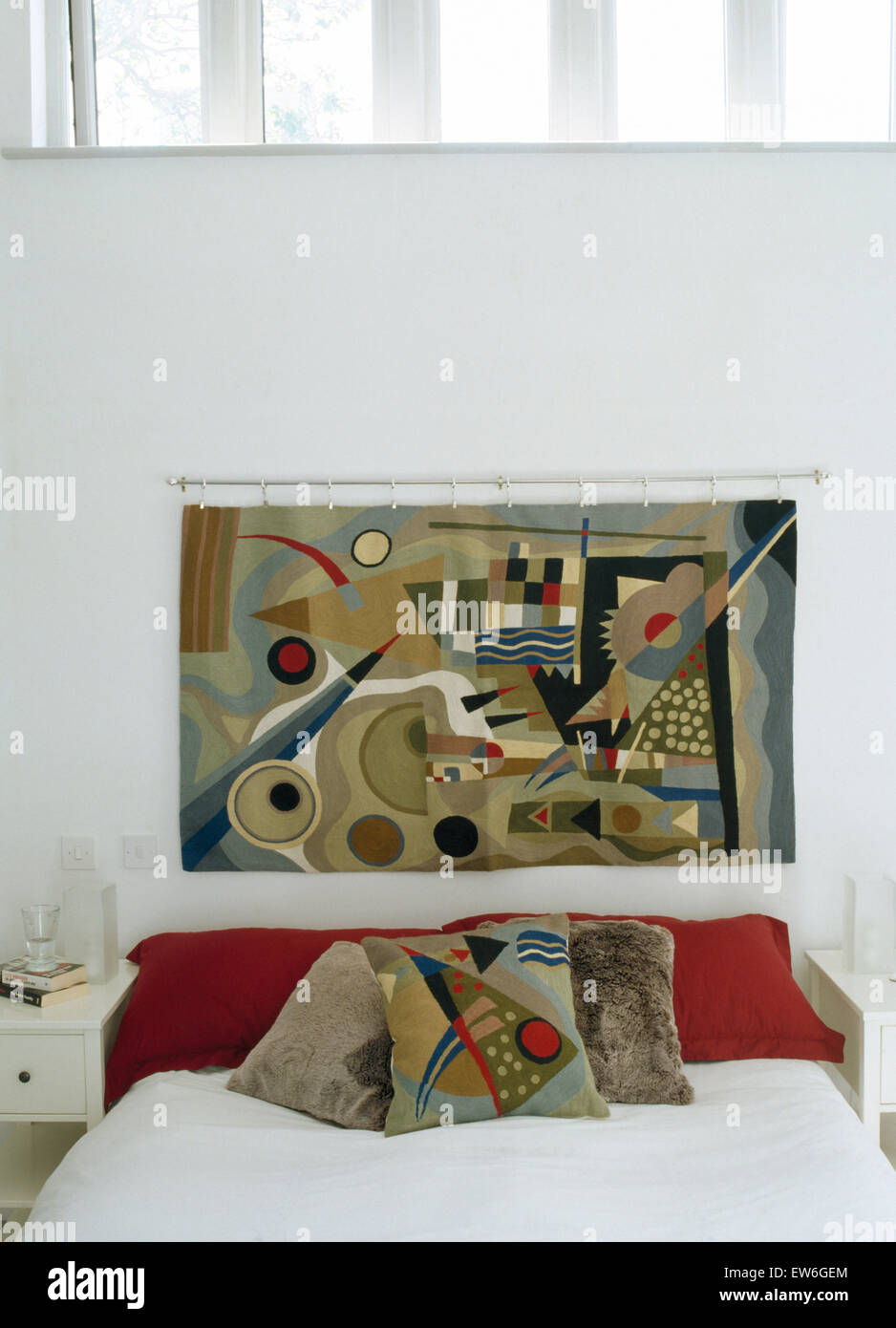 Parete astratta appeso sopra il letto con rosso e cuscini modellato in una moderna camera da letto Foto Stock