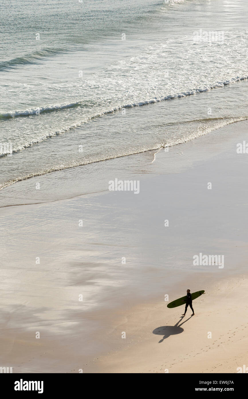 Un surfista passeggiate lungo la spiaggia di Sagres Portogallo. Foto Stock