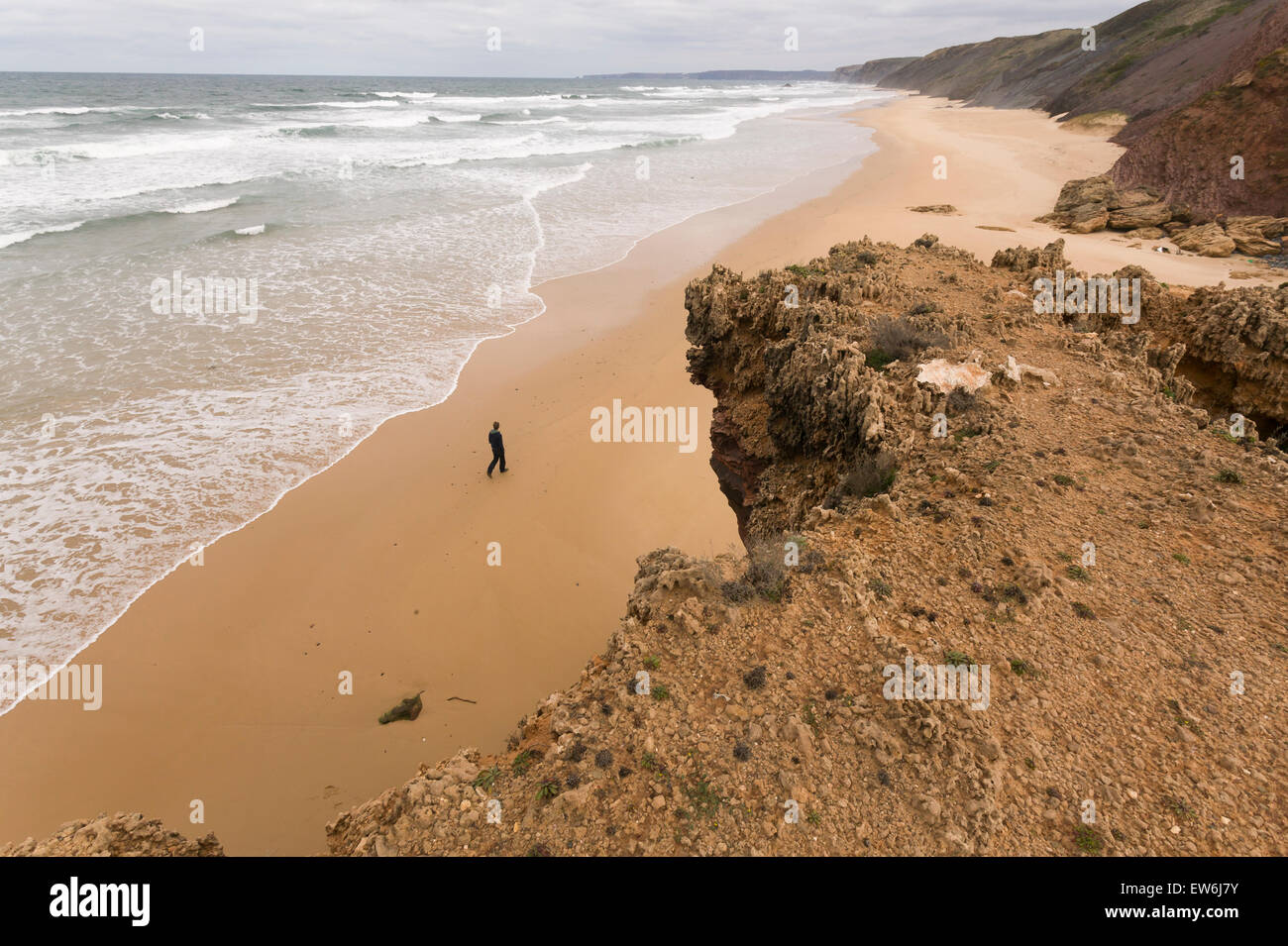 Un uomo cammina lungo e vuoto spiaggia vicino a Bordeira nella regione di Algarve in Portogallo. Foto Stock