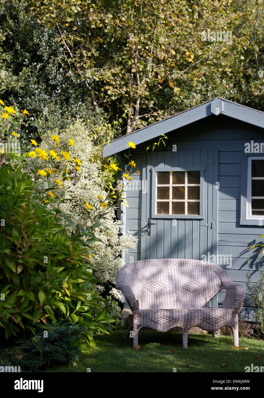 Bianco vimini divani davanti a pale in legno di colore blu casa estiva in un paese giardino Foto Stock