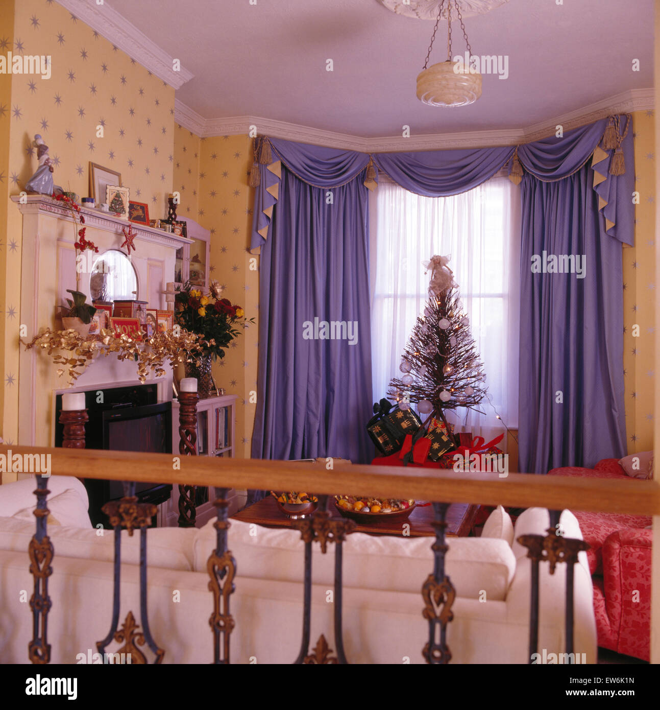 Viola e swagged tailed tende in novanta soggiorno decorato per il Natale Foto Stock