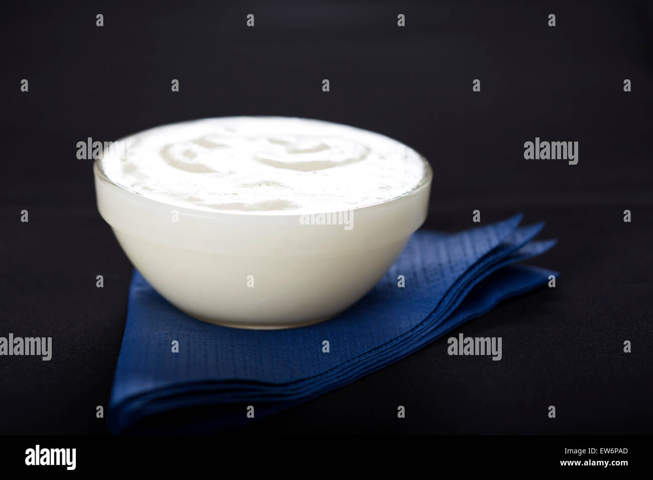 Ciotola di aglio fresco salsa dip sul tovagliolo blu con sfondo nero Foto Stock