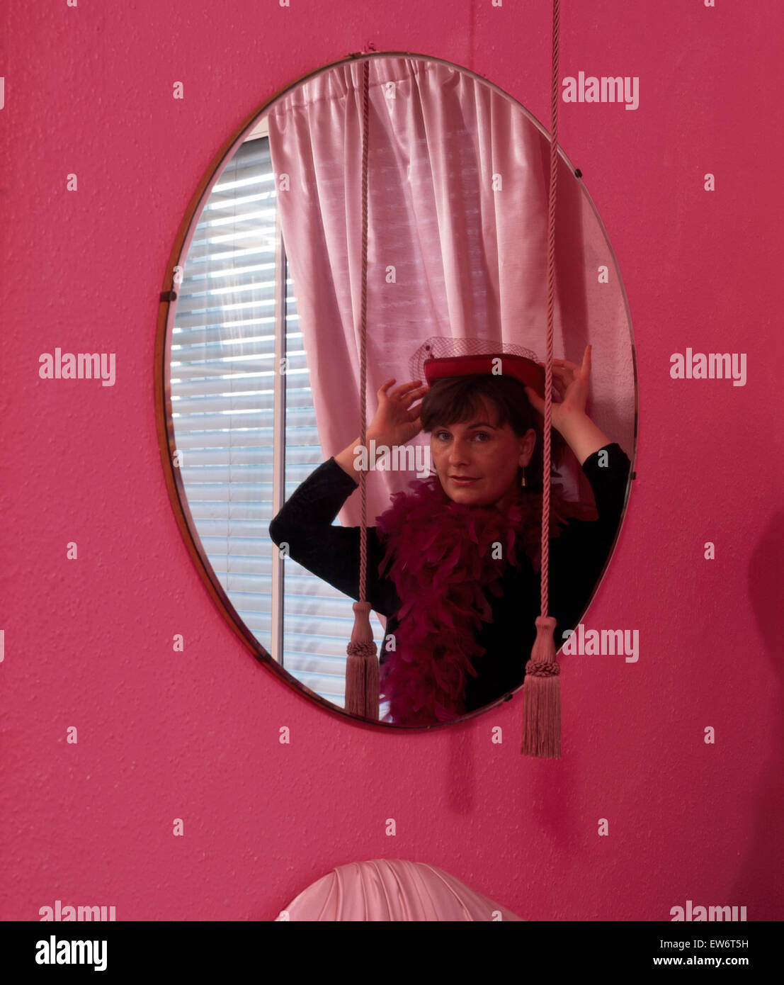 Ritratto di donna cercando su un cappello in uno specchio circolare per solo uso editoriale Foto Stock