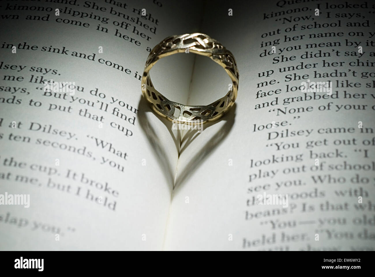 L'anello giacente su un libro aperto con heart-shaped ombra Foto Stock