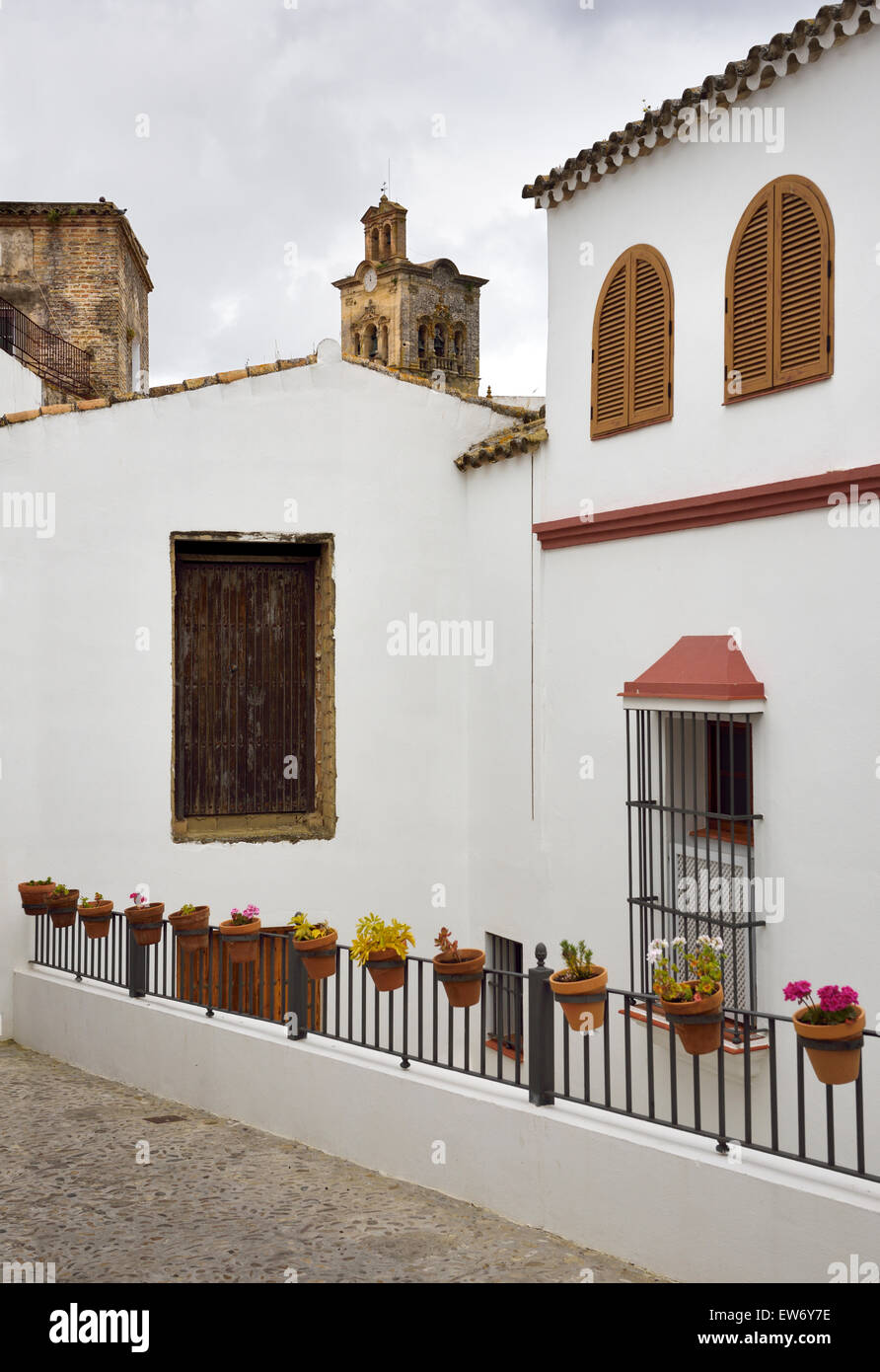 Chiesa di San Pietro campanile con le sue case dipinte di bianco e fiori in vasi di argilla di Arcos de la Frontera in Spagna Foto Stock