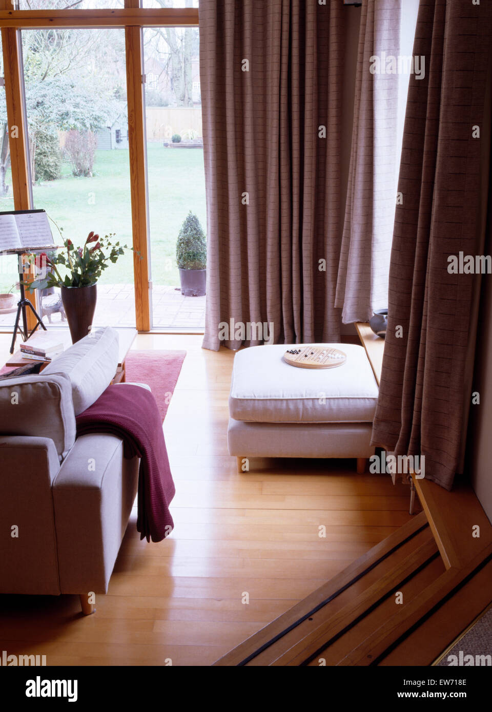 Passi verso il basso per soggiorno interno con pavimento in legno e tende in folle Foto Stock