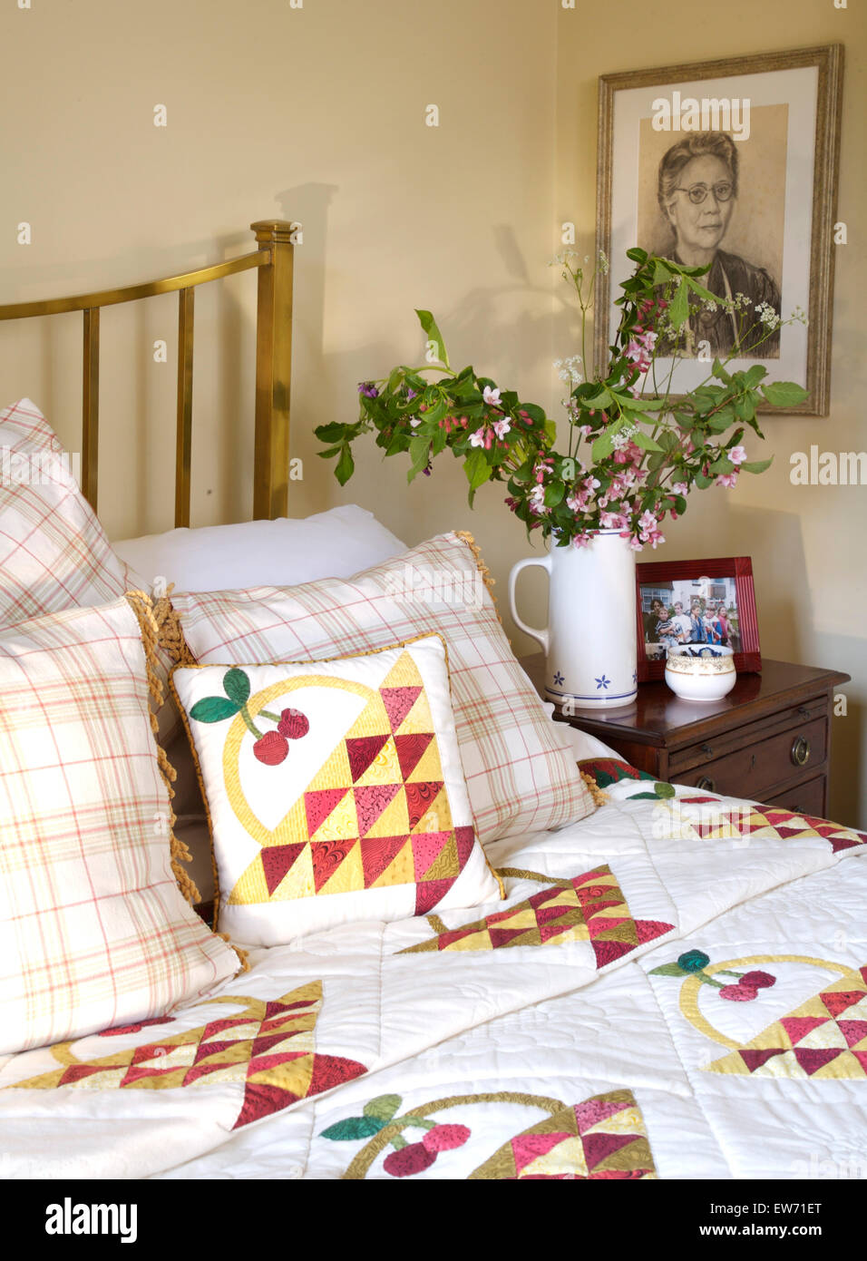 Letto in ottone con un mosaico e verificati e patchwork di cuscini e un tavolino con una brocca di fiore rosa Foto Stock
