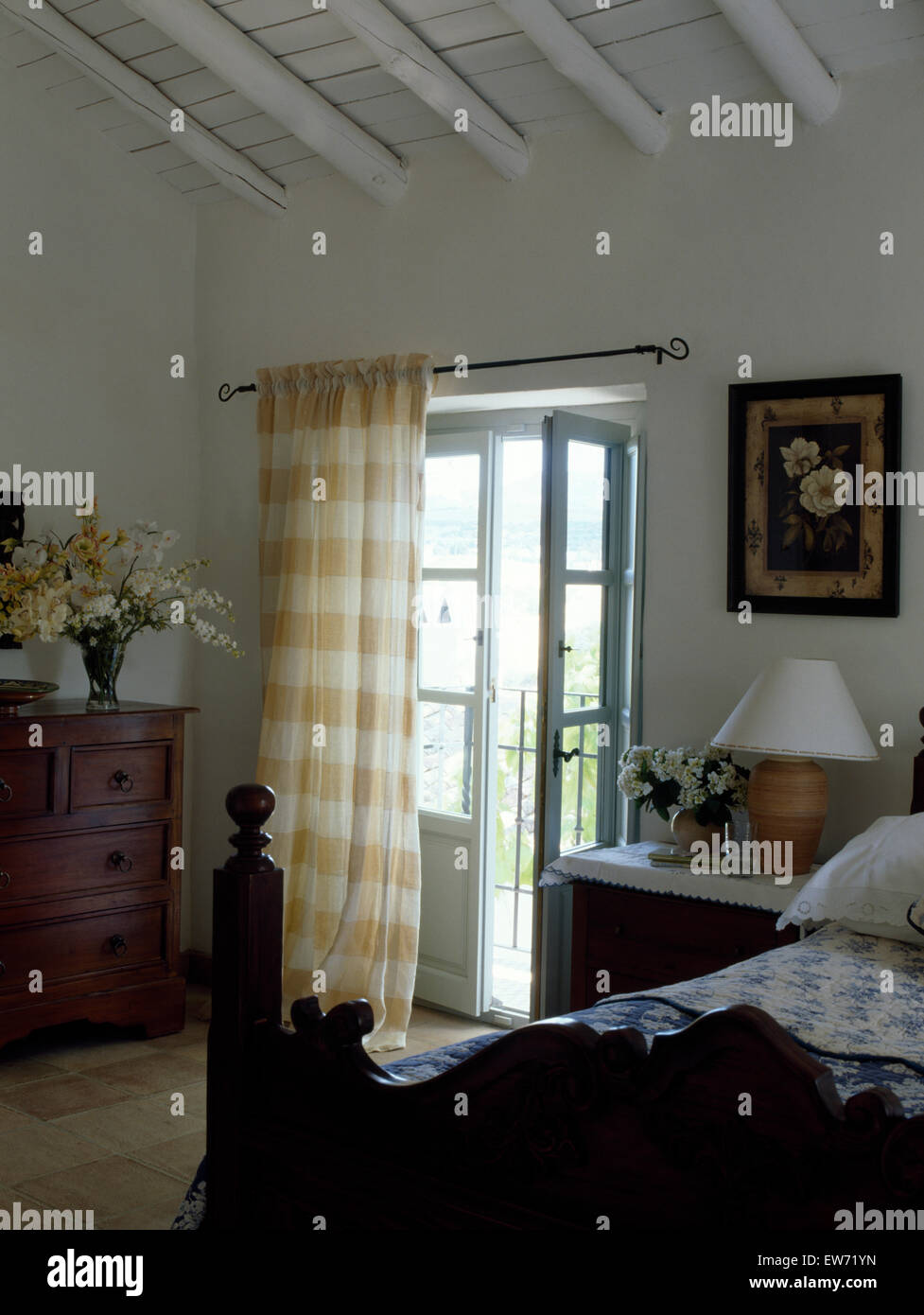 Antico letto in legno nel paese francese camera da letto con giallo controllato tendina su finestre Francesi al balcone Foto Stock