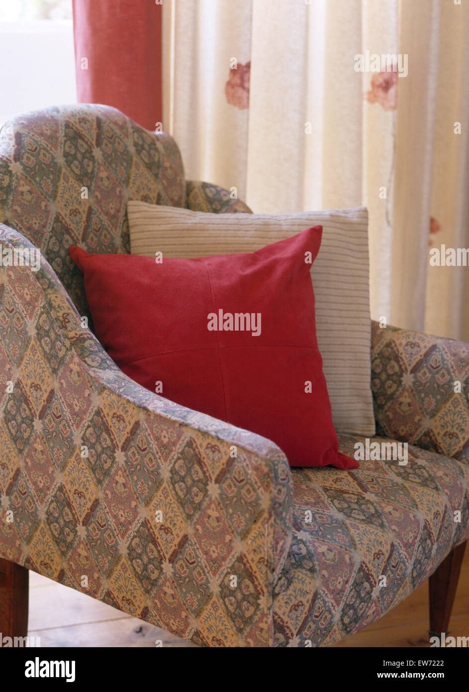 Close-up di una poltroncina imbottita con rosso e cuscini a righe Foto Stock