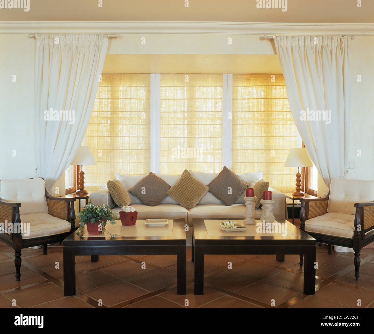 Tende bianche e split persiane di canna sulla finestra in spagnolo soggiorno  con due tavolini da caffè e grande divano Foto stock - Alamy