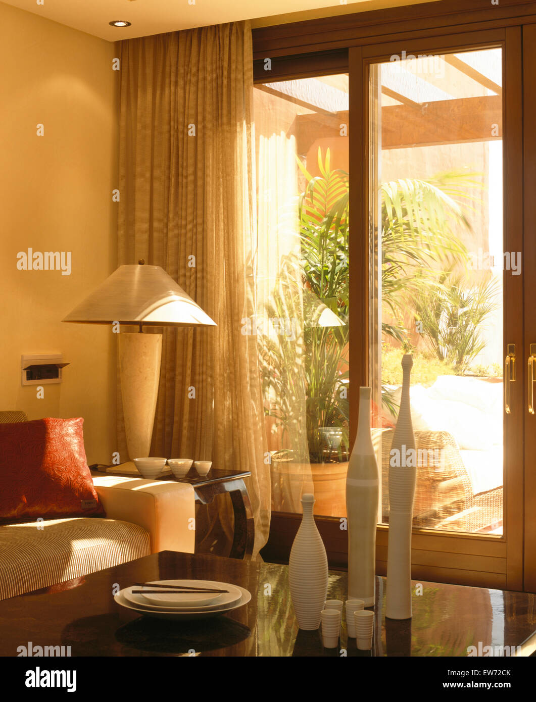 Lampada alti sul lato tavolo accanto a vetro porte di patio con voile oscuranti nel salotto di villa spagnola Foto Stock