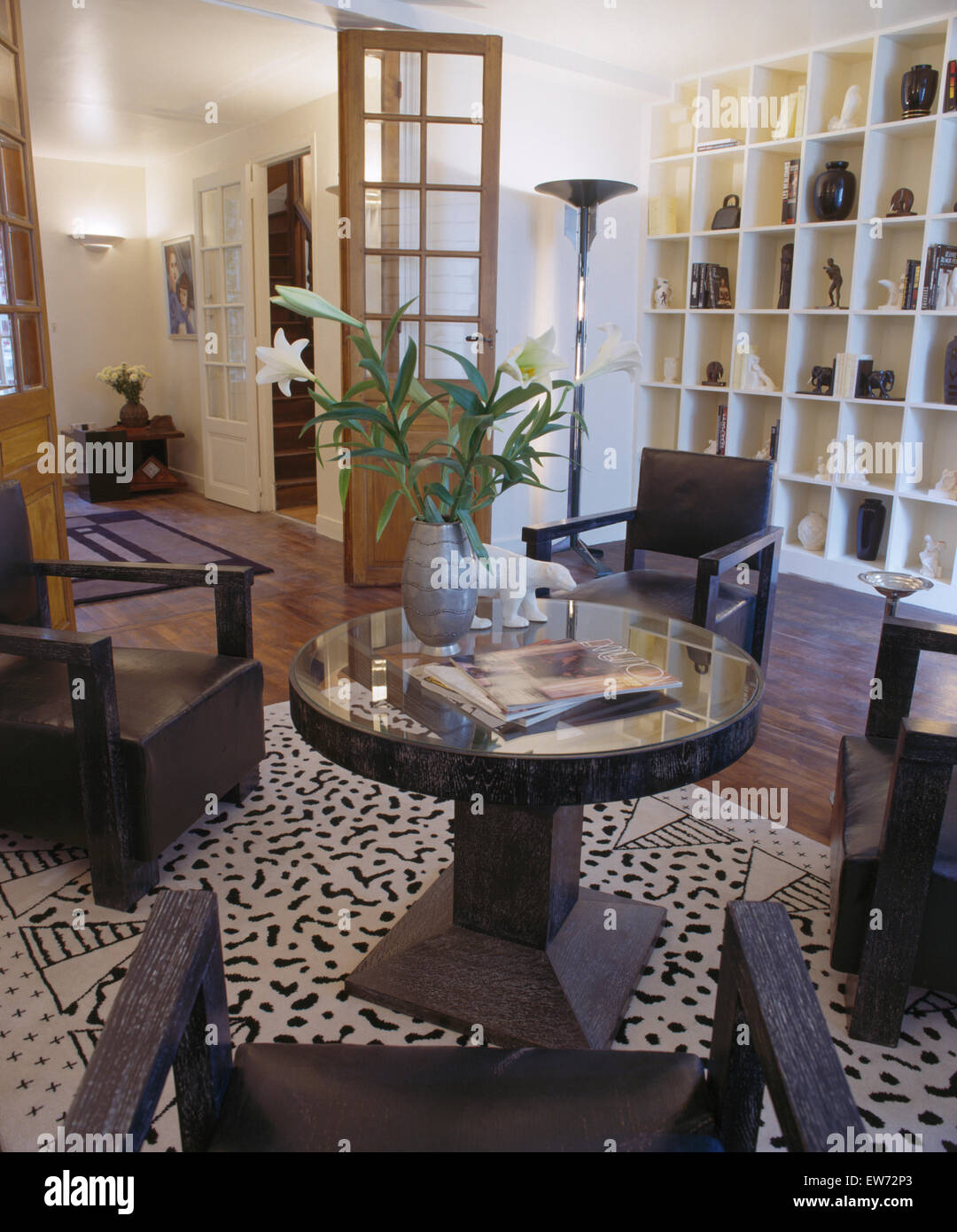 Vaso di gigli sulla tavola circolare con sedie nere in stile anni trenta area da pranzo con il cubo della scaffalatura e nero+tappeto bianco Foto Stock