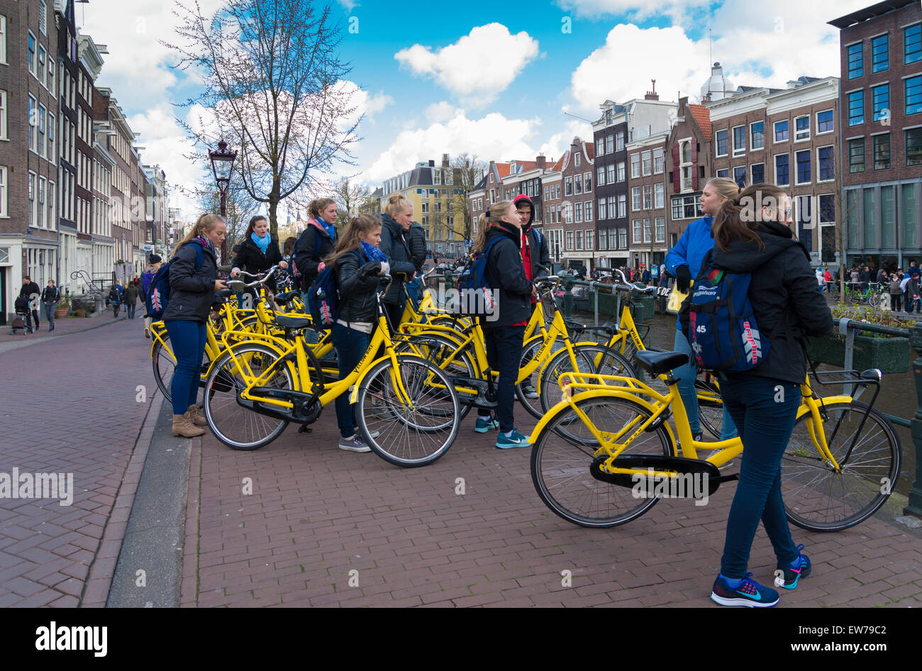 Gruppo di turisti su giallo biciclette a noleggio nel centro di amsterdam Foto Stock