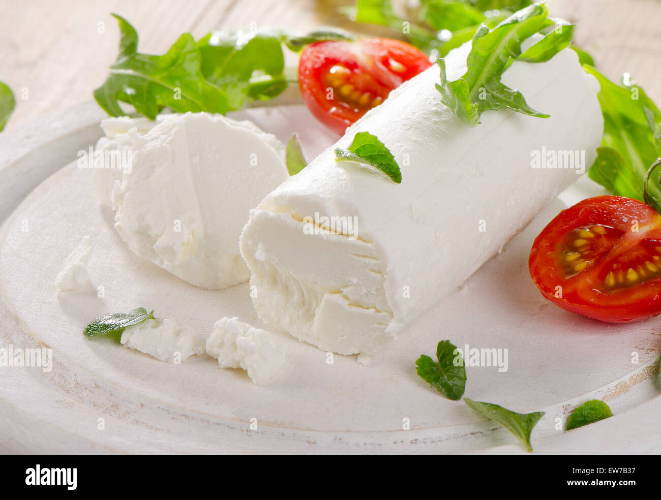 Formaggio di capra con insalata fresca e pomodori in un bianco tavolo di legno. Messa a fuoco selettiva Foto Stock