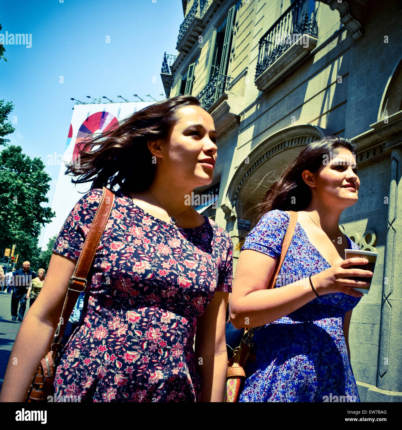 Due giovani donne che indossano abiti floreali camminando per strada. Barcellona, in Catalogna, Spagna. Foto Stock