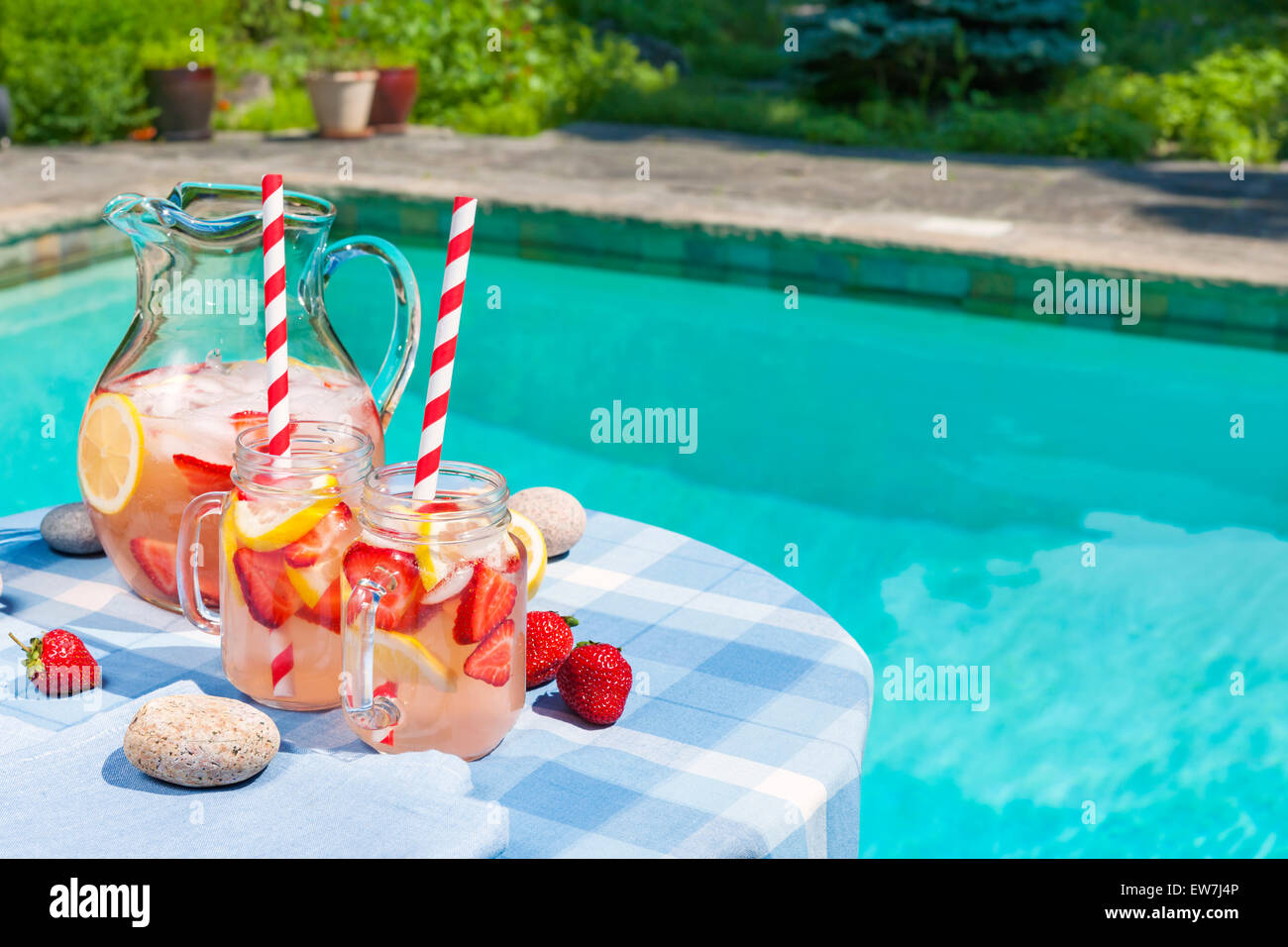 Di ghiaccio freddo in casa fragola limonata in caraffa e bicchieri di carta con cannucce in estate outdoor pool side tabella più spazio di copia Foto Stock