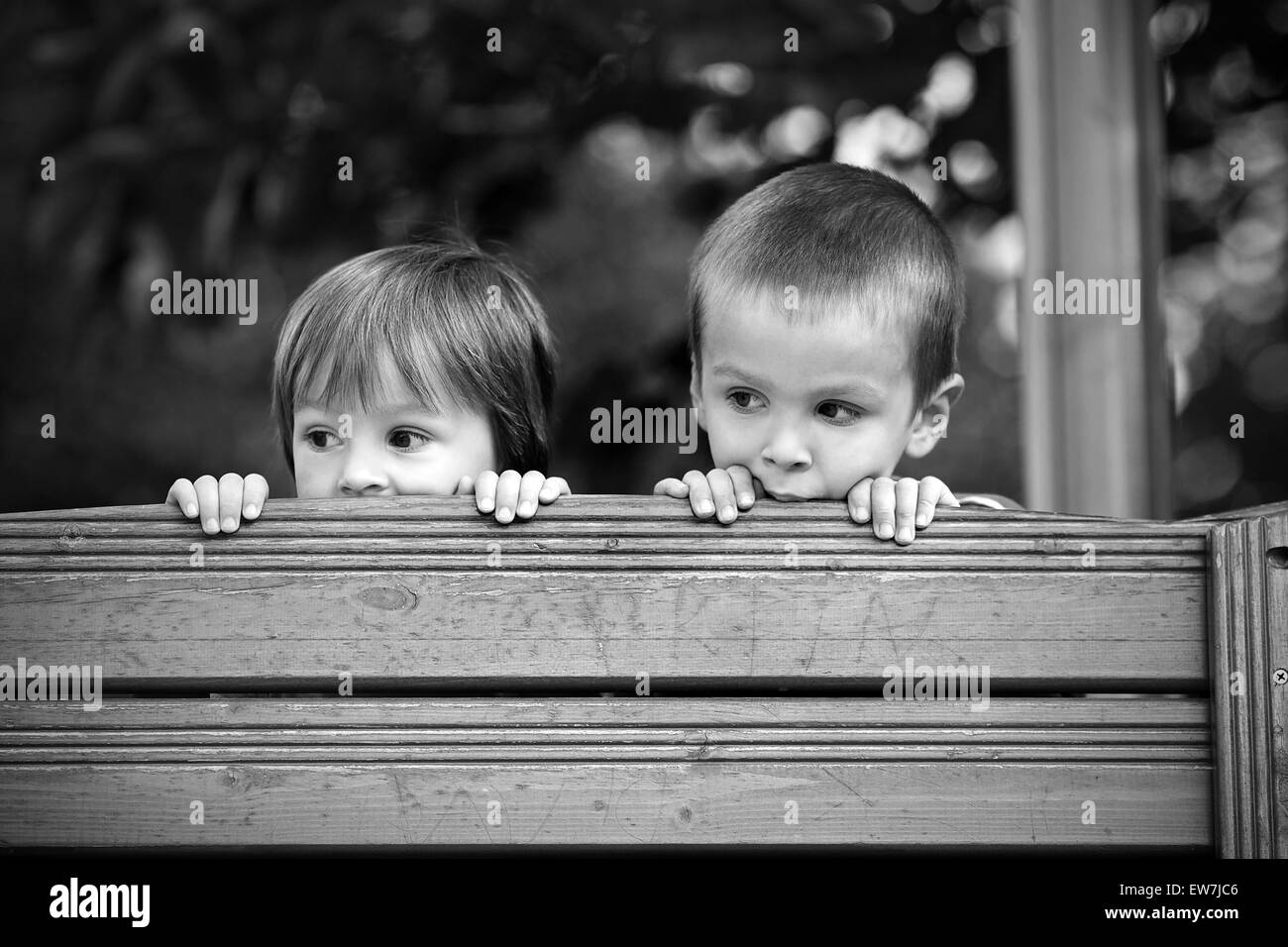 Due curiose boys, cerca su una parete in legno Foto Stock