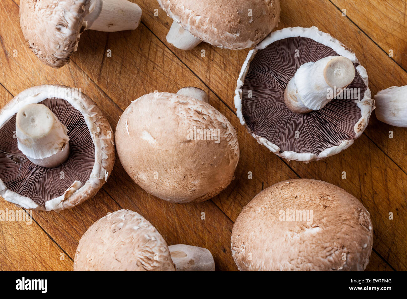Big marrone di funghi champignon sparsi sul tagliere di legno in pianura e capovolto da sopra Foto Stock