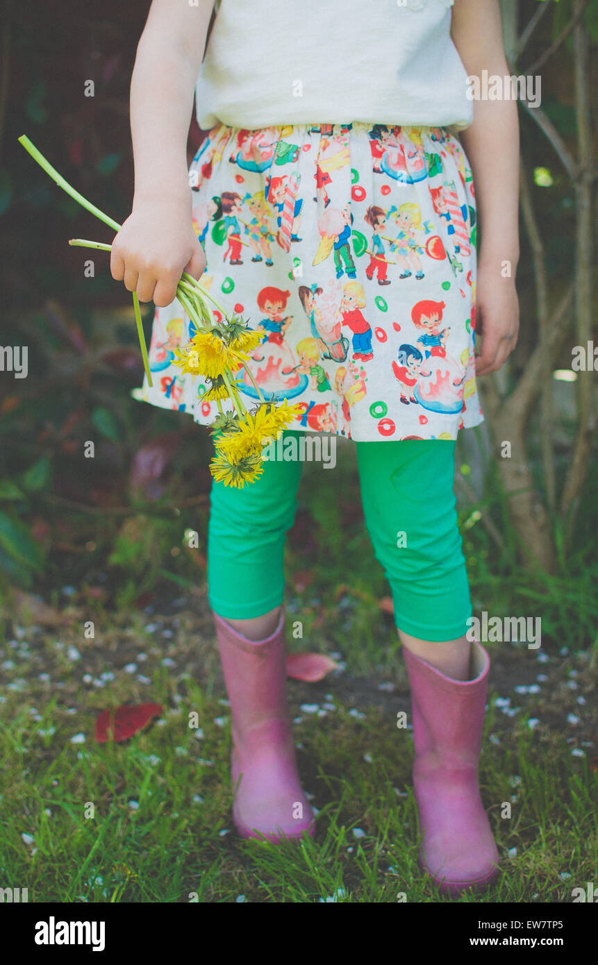 Sezione bassa di una ragazza con i fiori di tarassaco Foto Stock