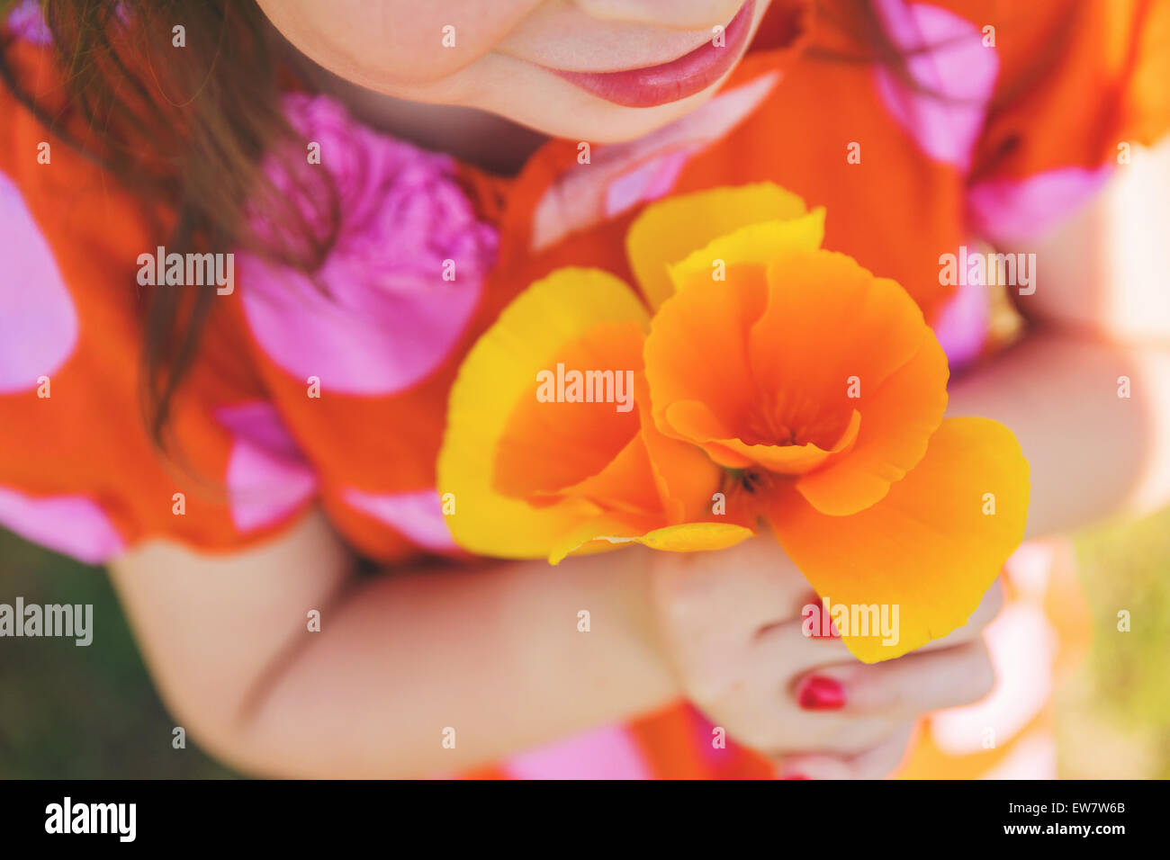 Primo piano di una ragazza che tiene papaveri arancioni Foto Stock