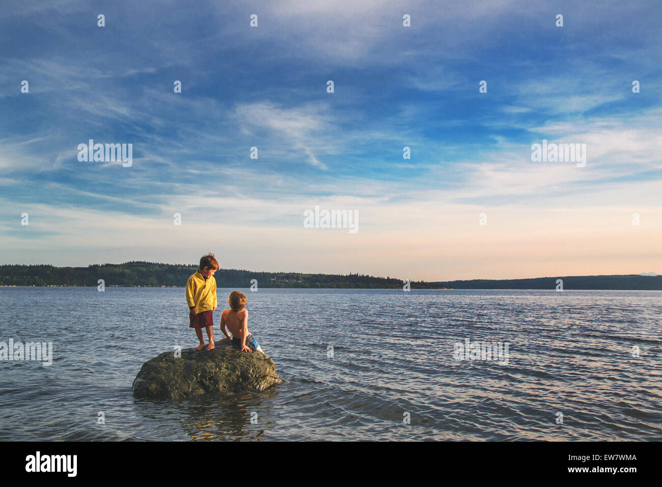 Due ragazzi seduti su una roccia nel mare Foto Stock