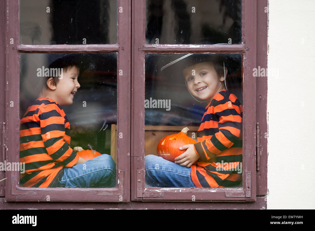 Due simpatici ragazzi, seduti su una finestra con zucche, sorridente Foto Stock