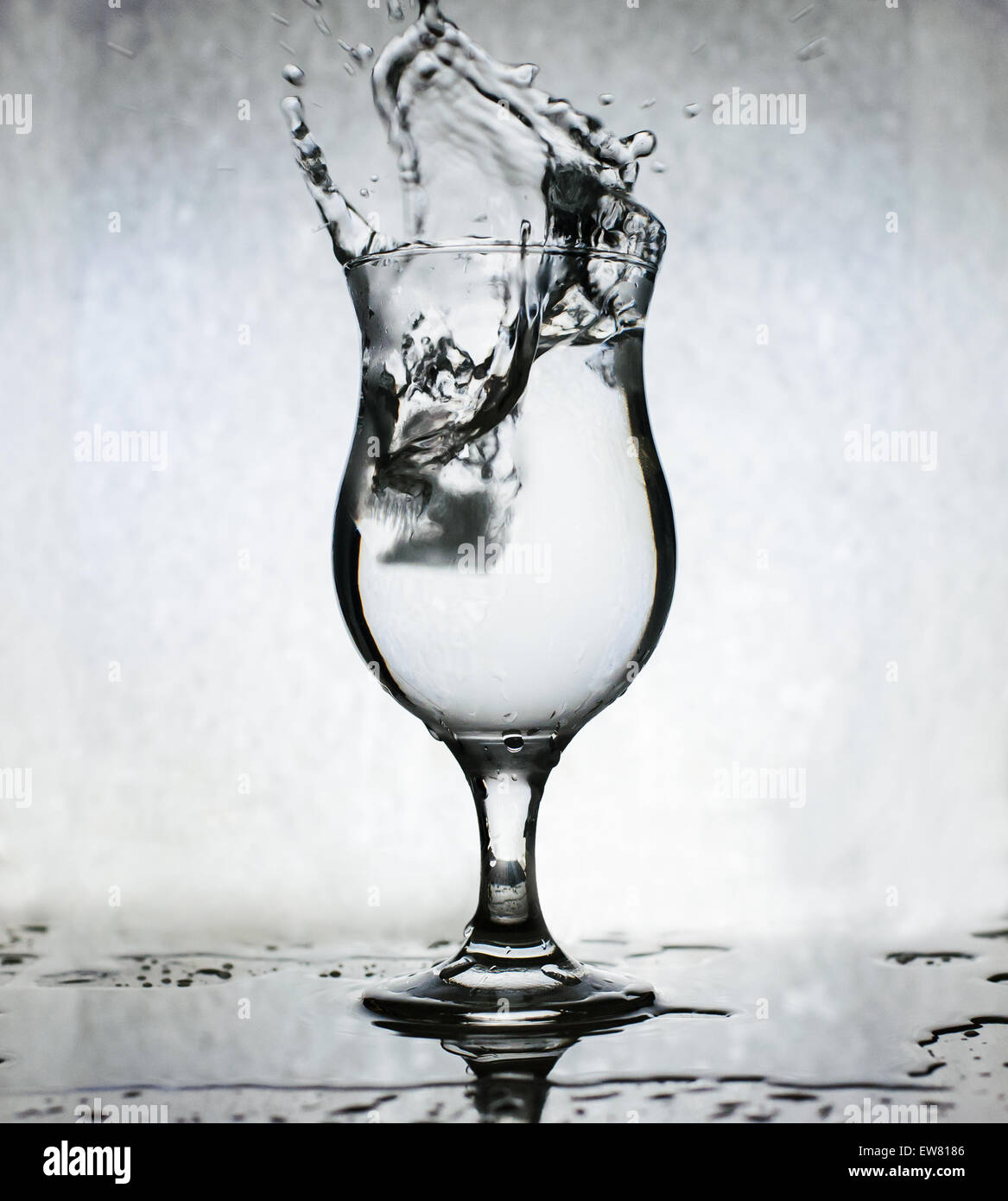 Cubetti di ghiaccio schizzi in un bicchiere di acqua, sfocatura del movimento Foto Stock