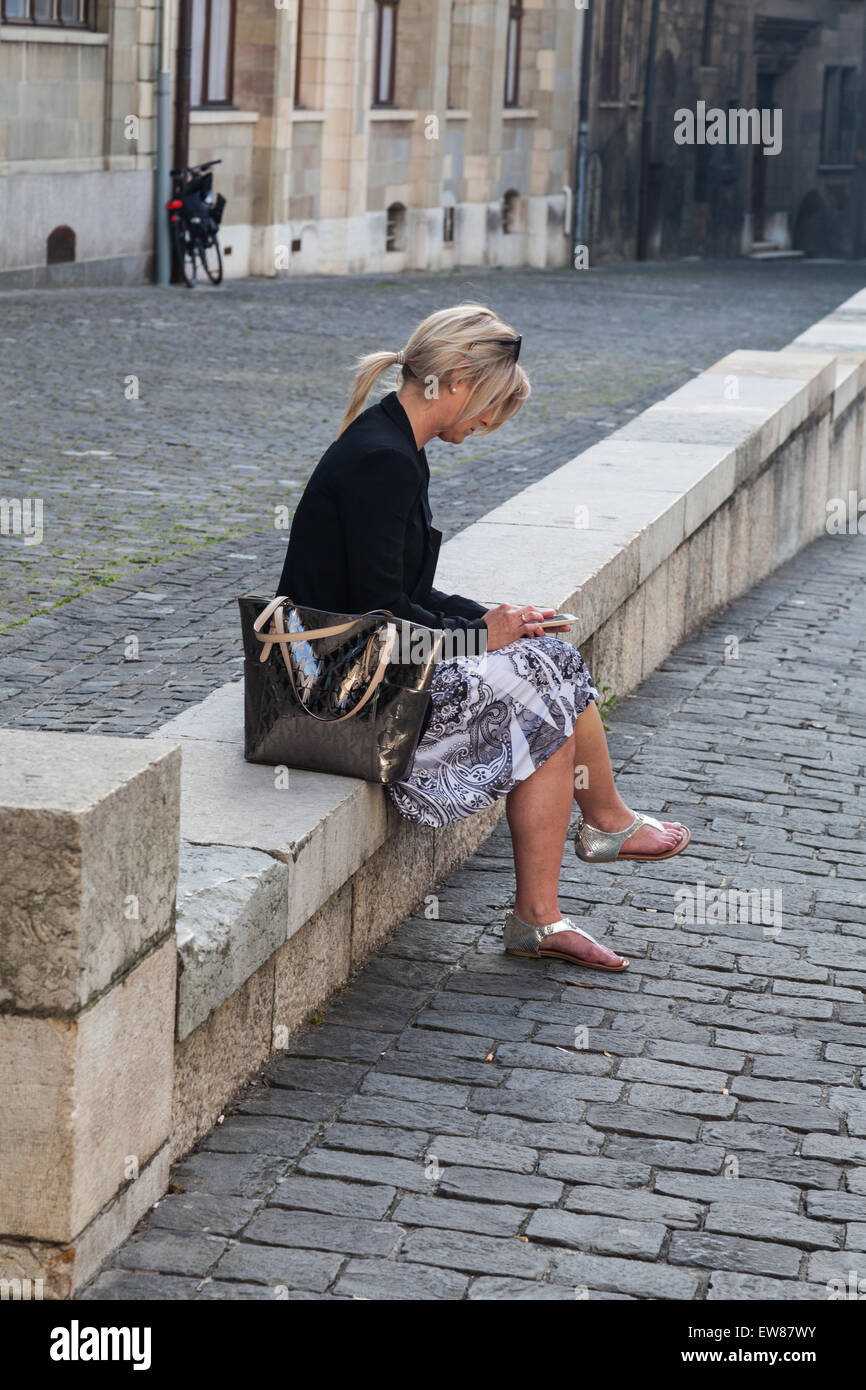 Distratti donna inviando un messaggio di testo con il suo smart phone Foto Stock