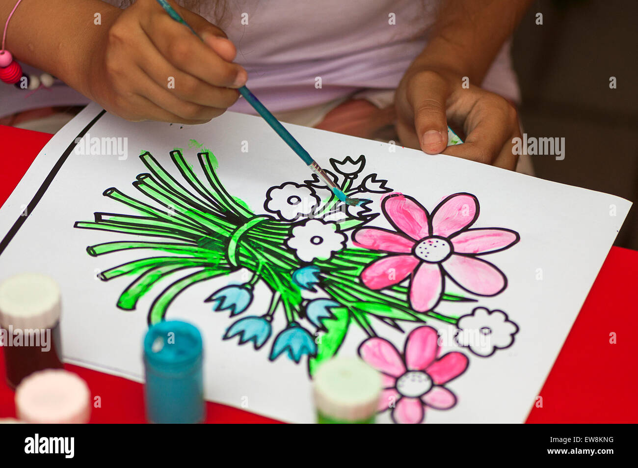 Bambino verniciatura dopo un fiore disegno del contorno Foto Stock