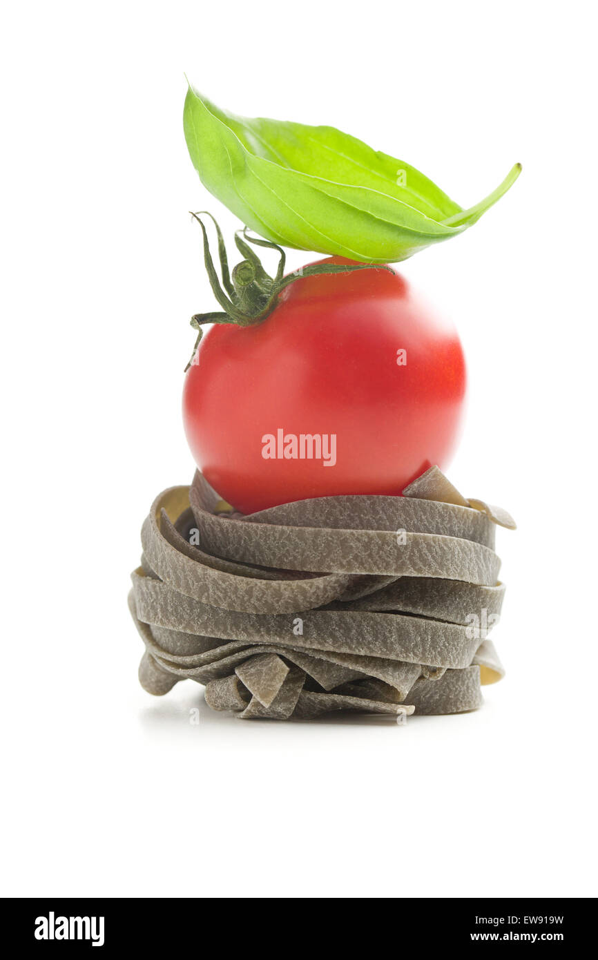 Tagliatelle con pomodoro e basilico foglie su sfondo bianco Foto Stock