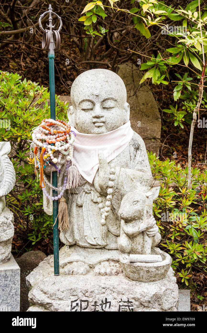 Giappone, Miyajima. Daisho-in. Piccola pietra Jizo statua di standing monaco buddista che trasportano un metallo shakujo con sei anelli. Il coniglio si inginocchia accanto a lui Foto Stock