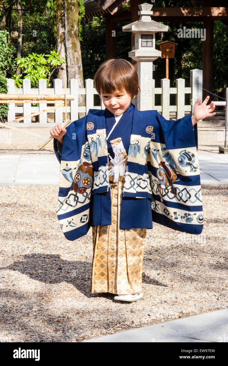 Bambino caucasico, boy, 5 anno di età, vestita in kimono giapponese e il  piano di calpestio con cautela attraverso sacrario scintoista cortile come  se lo spunto da fermi senza un suono Foto