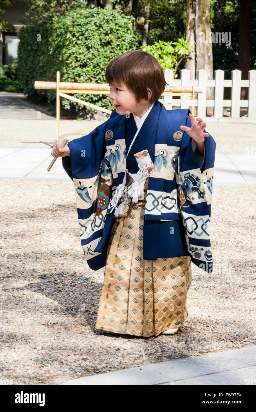 Bambino caucasico, boy, 5 anno di età, vestita in kimono giapponese e il  piano di calpestio con cautela attraverso sacrario scintoista cortile come  se lo spunto da fermi senza un suono Foto