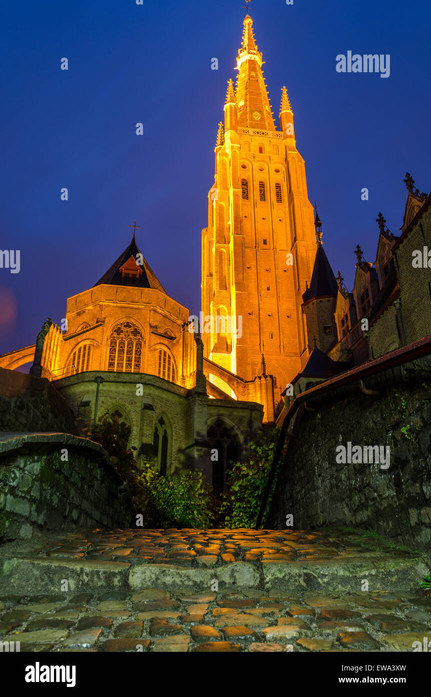 Onze Lieve Vrouwekerk in Bruges visto di notte guardando attraverso un ponte sul canale Foto Stock