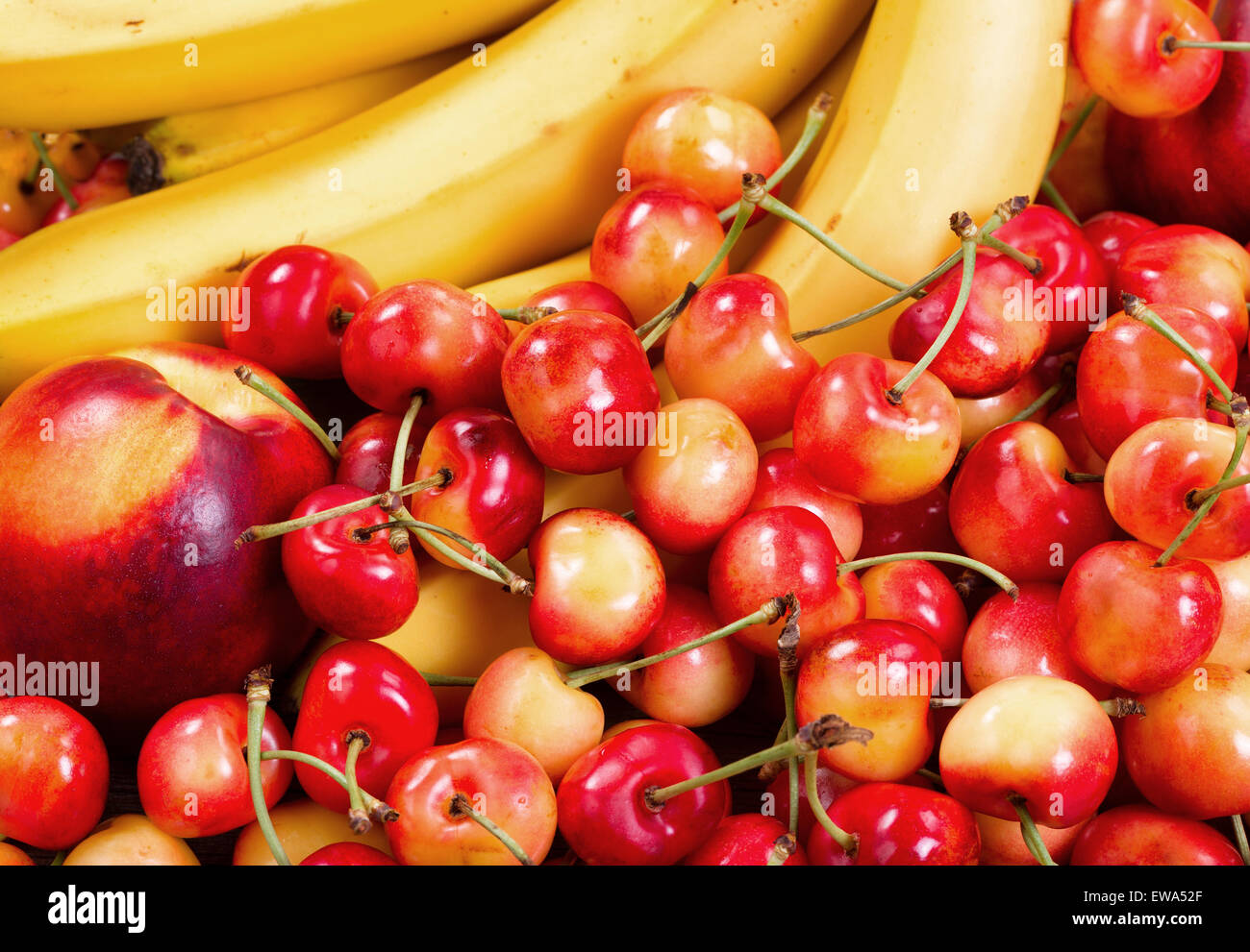 In prossimità di una nuova pila di frutta composta di ciliegie, di pesche e di banane. Layout in pieno il formato del frame. Foto Stock