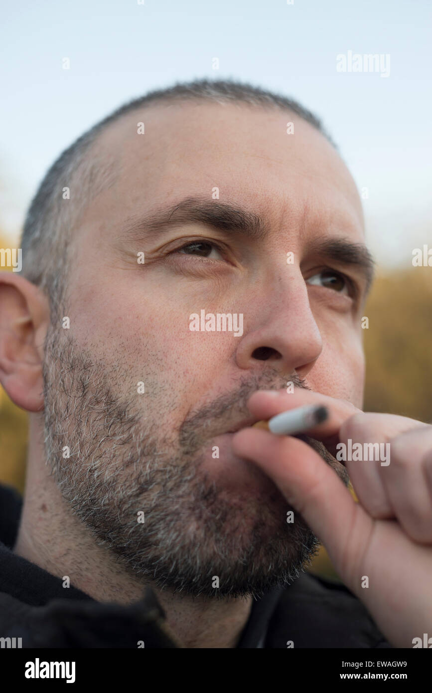 Ritratto di un uomo di barba di fumare all'aperto Foto Stock