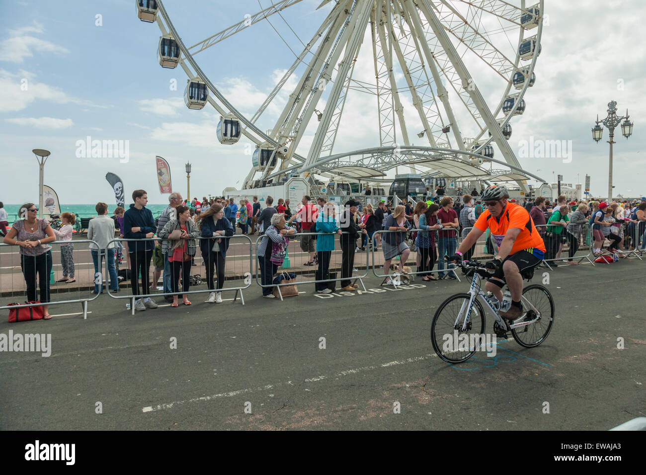 Brighton, Regno Unito. Il 21 giugno, 2015. Ciclista in una elevata visibilità camicia passa davanti di spettatori. Ruota di Brighton in distanza. Credito: Slawek Staszczuk/Alamy Live News Foto Stock