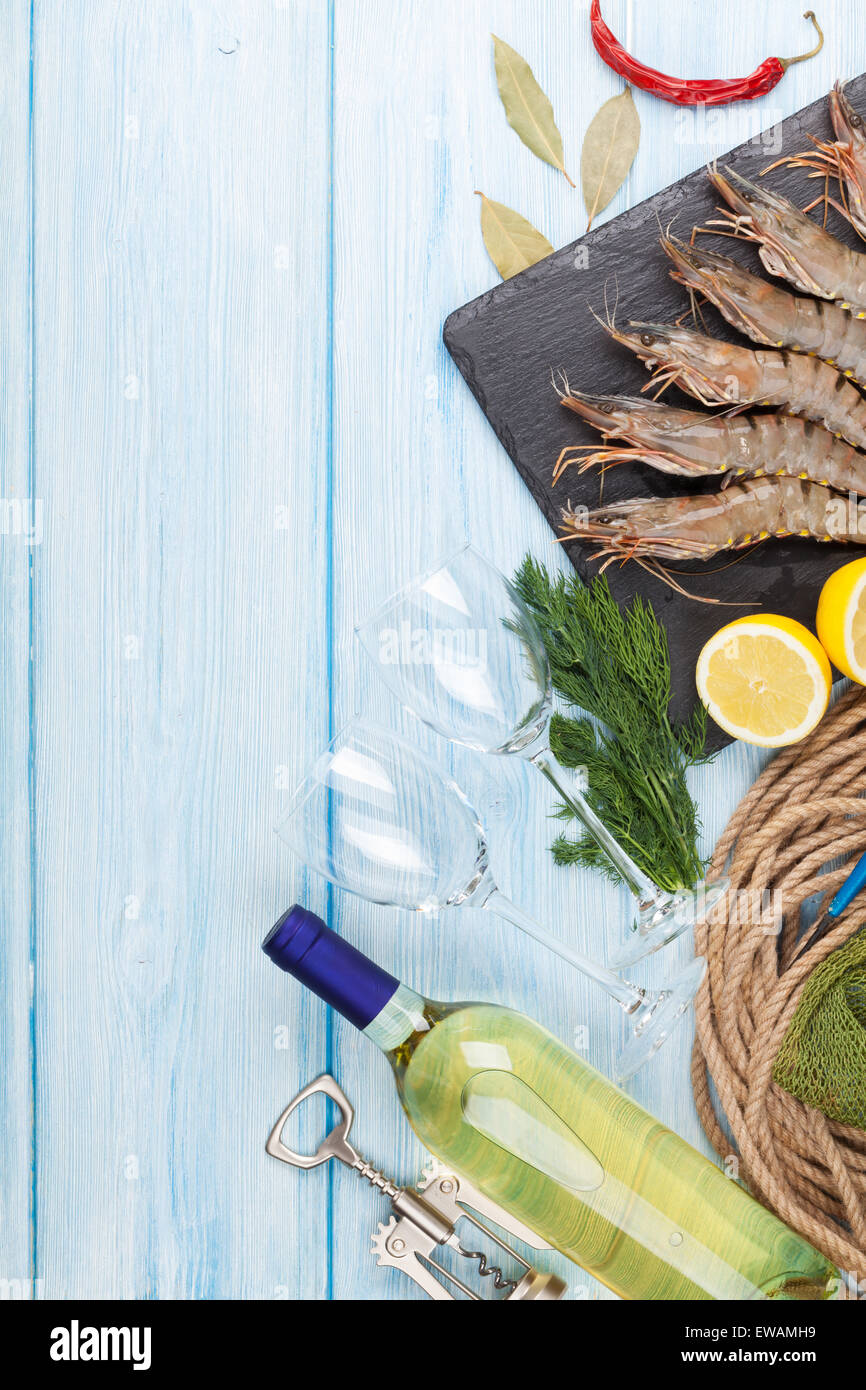 Crudo fresco gamberoni, spezie e vino bianco su tavola di legno con spazio di copia Foto Stock