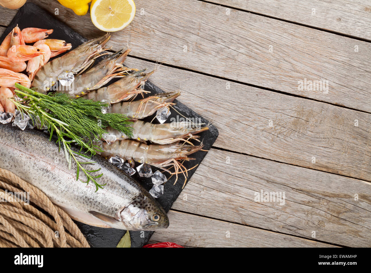 Crudo fresco il cibo del mare con spezie sulla lastra di pietra su un tavolo di legno dello sfondo. Vista da sopra con lo spazio di copia Foto Stock