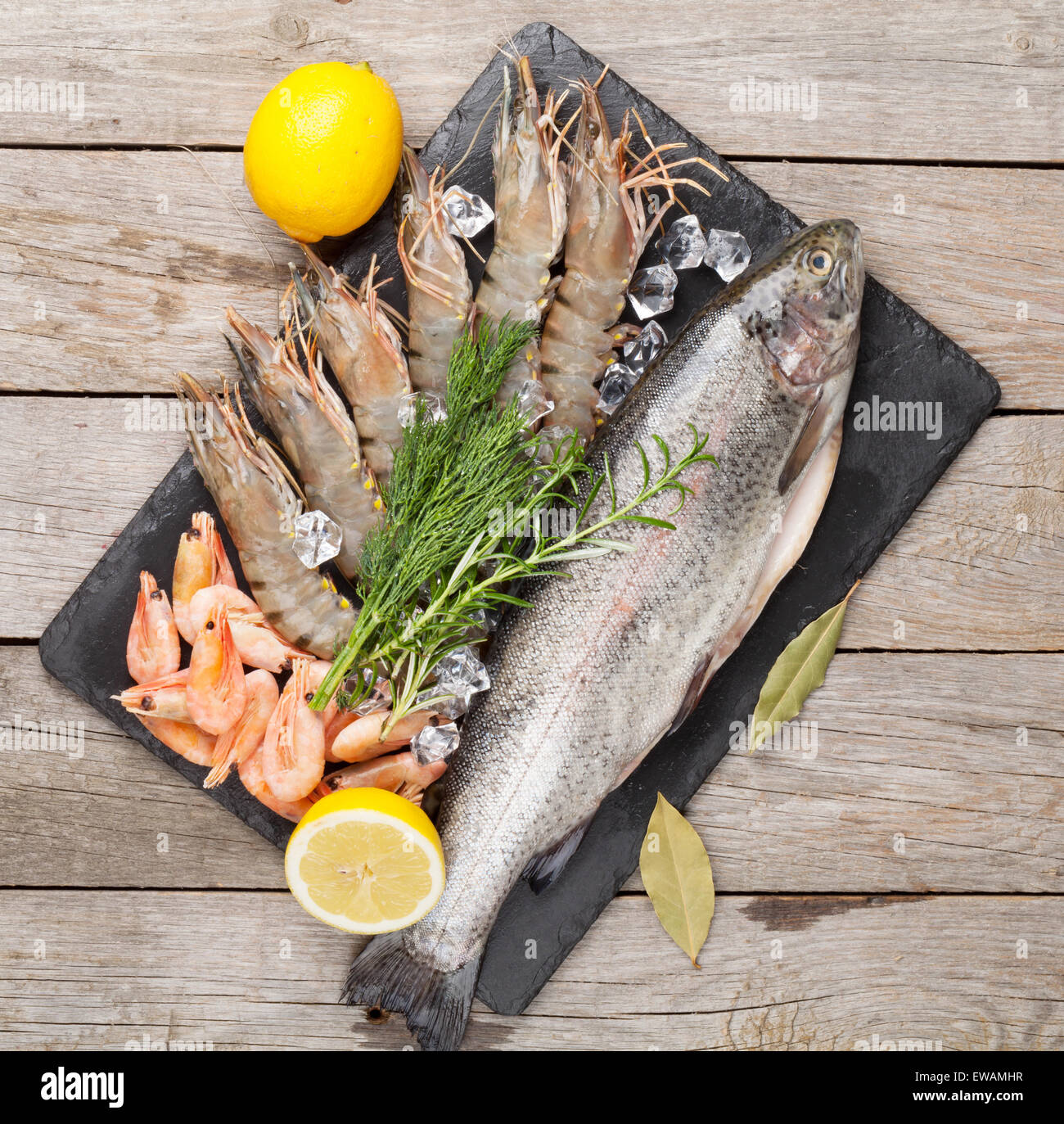 Crudo fresco il cibo del mare con spezie sulla lastra di pietra su un tavolo di legno dello sfondo. Vista superiore Foto Stock