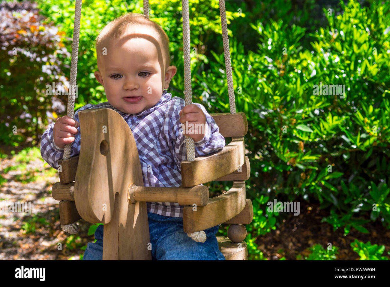 Carino il bambino in una struttura in legno swing Foto Stock