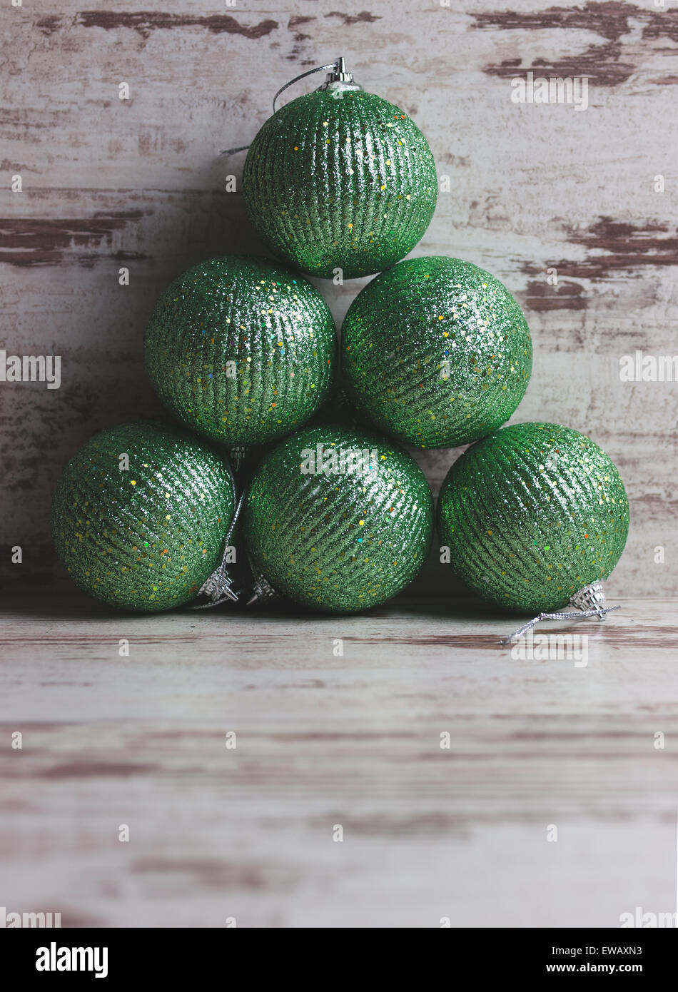 Verde palle di Natale in una pila su sfondo di legno in un studio shot Foto Stock