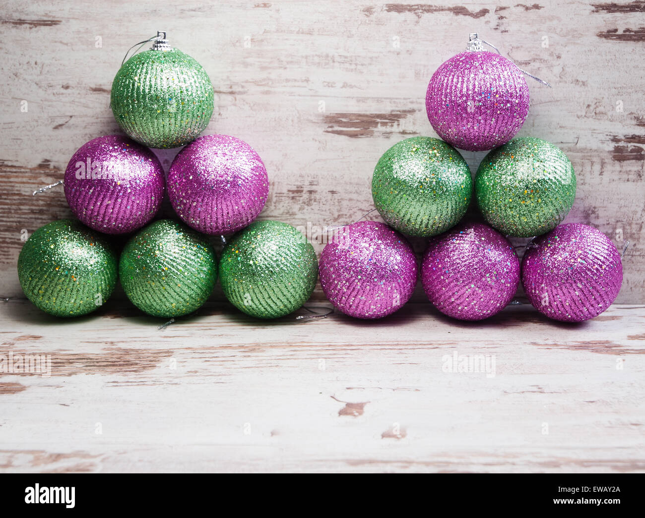 Di colore rosa e verde palle di Natale in una pila su sfondo di legno in un studio shot Foto Stock