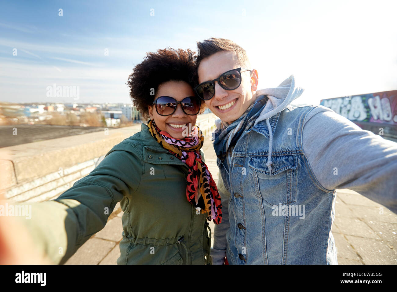 Felice coppia adolescente tenendo selfie sulla strada di città Foto Stock