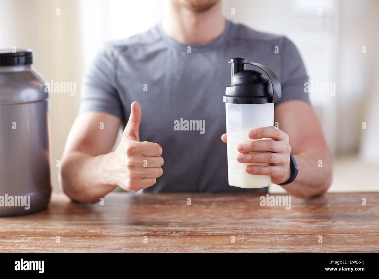 L'uomo con la proteina agitare la bottiglia che mostra pollice in alto Foto Stock
