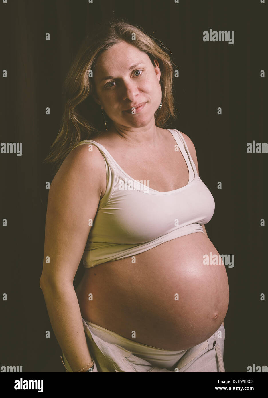 Donna incinta guardando la fotocamera in un ritratto in studio Foto Stock